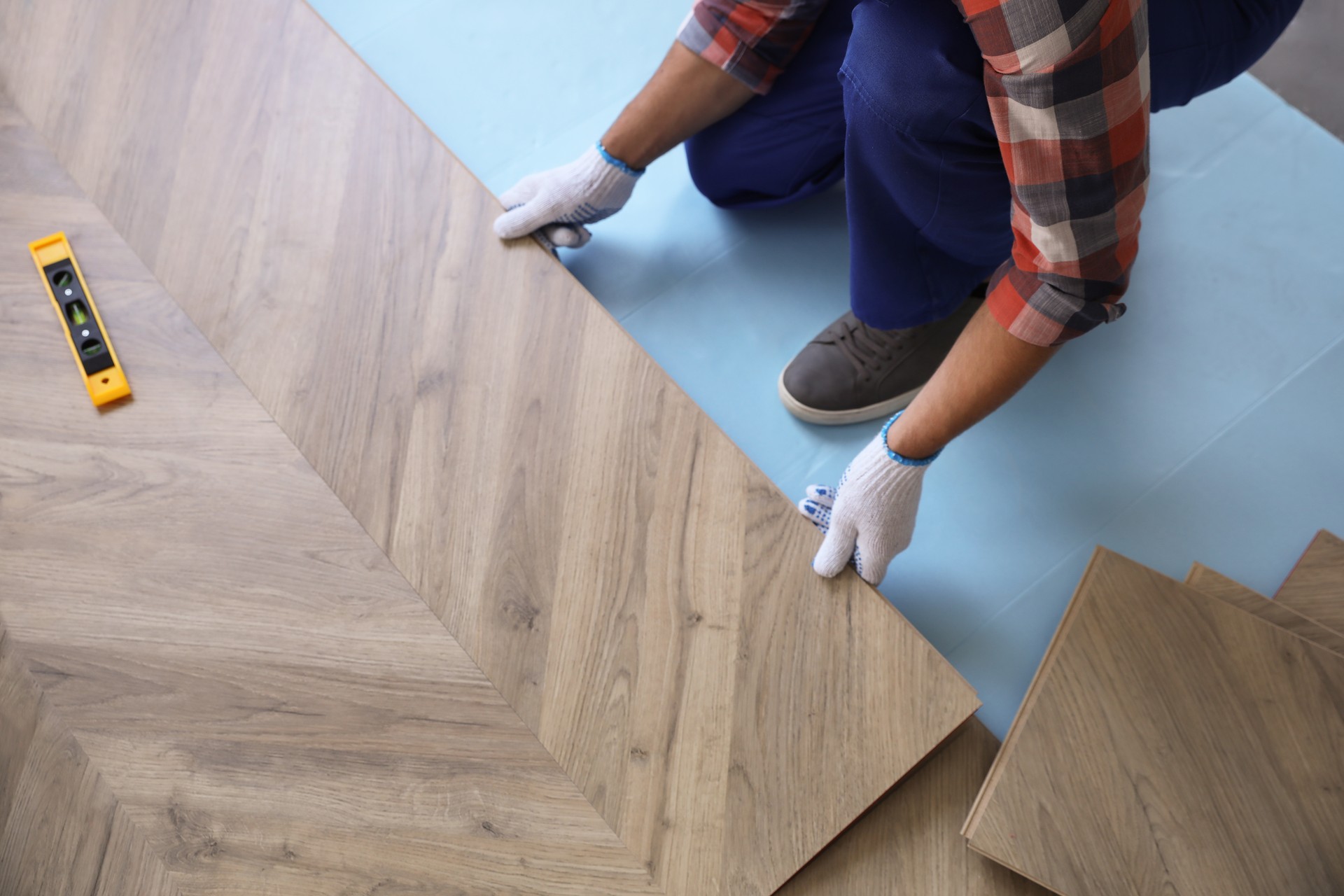 Worker installing laminated wooden floor indoors, closeup